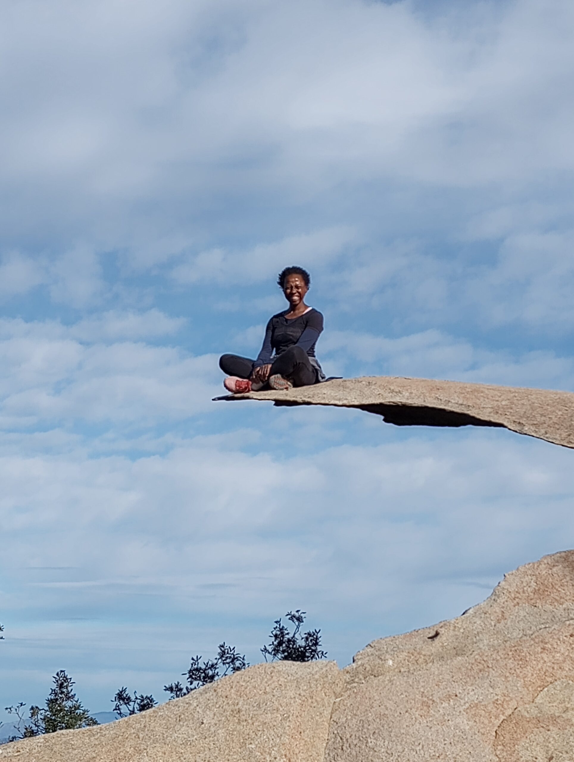 fit woman sitting on the tip of mount woodson